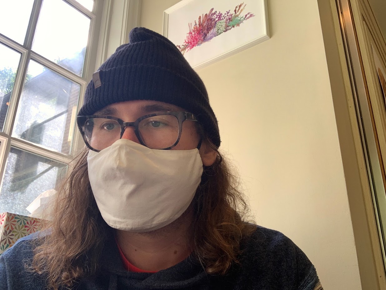 A picture of Chris Davies from 2021. He is wearing a red winter hat, glasses and a face mask as covid is real and a problem